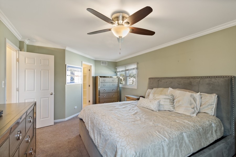 1164 Devonshire Road Buffalo Grove, IL 60089 - Photo 9 of 20 a spacious bedroom with a bed and a chandelier