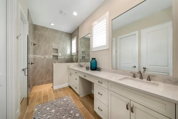 a spacious bathroom with a double vanity sink a mirror and a shower