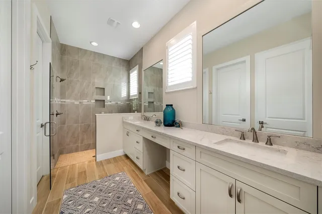 a spacious bathroom with a double vanity sink a mirror and a shower