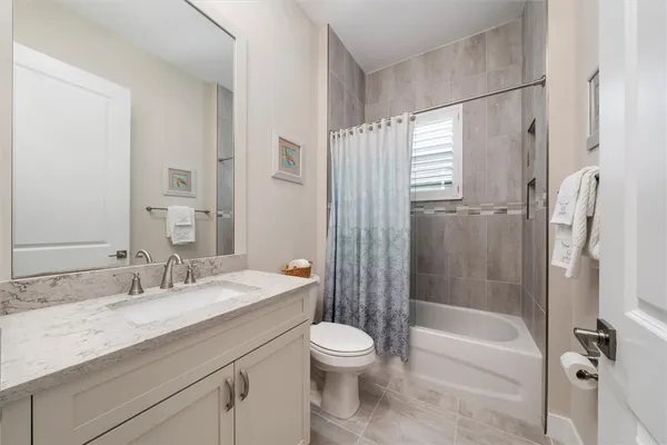 a bathroom with a granite countertop sink a toilet and shower