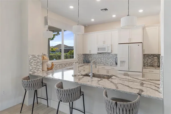 a kitchen with kitchen island granite countertop a sink and a refrigerator