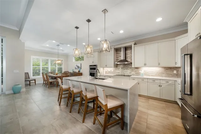 a large kitchen with kitchen island a dining table chairs and white cabinets