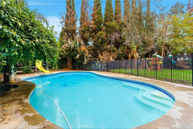 a view of a swimming pool with a patio and a yard