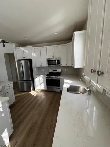 a kitchen with granite countertop a refrigerator stove and sink