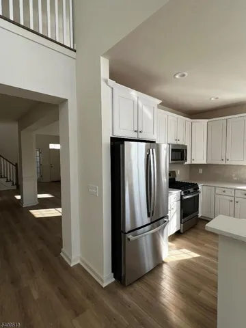 a kitchen with granite countertop a refrigerator stove and wooden floor
