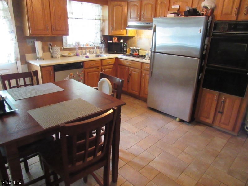 1033 Grove Street North Brunswick, NJ 08902 - Photo 4 of 14 a kitchen with stainless steel appliances granite countertop a refrigerator a sink a stove a dining table and chairs