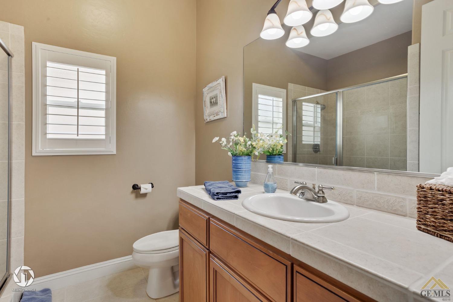 Undisclosed Address Bakersfield, CA 93311 - Photo 43 of 58 a bathroom with a sink a large mirror and a toilet