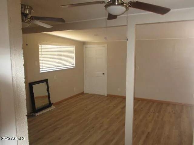 a view of an empty room with a window and wooden floor