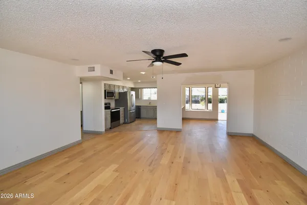 a view of an empty room with a kitchen and wooden floor