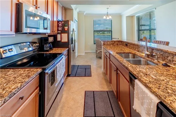a kitchen with granite countertop a stove a sink and a refrigerator
