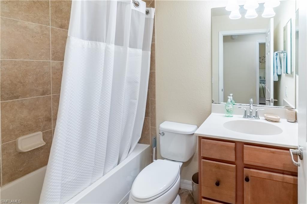 9517 Avellino Way, Unit 2214 Naples, FL 34113 - Photo 5 of 44 a bathroom with a sink a toilet a mirror and shower curtain