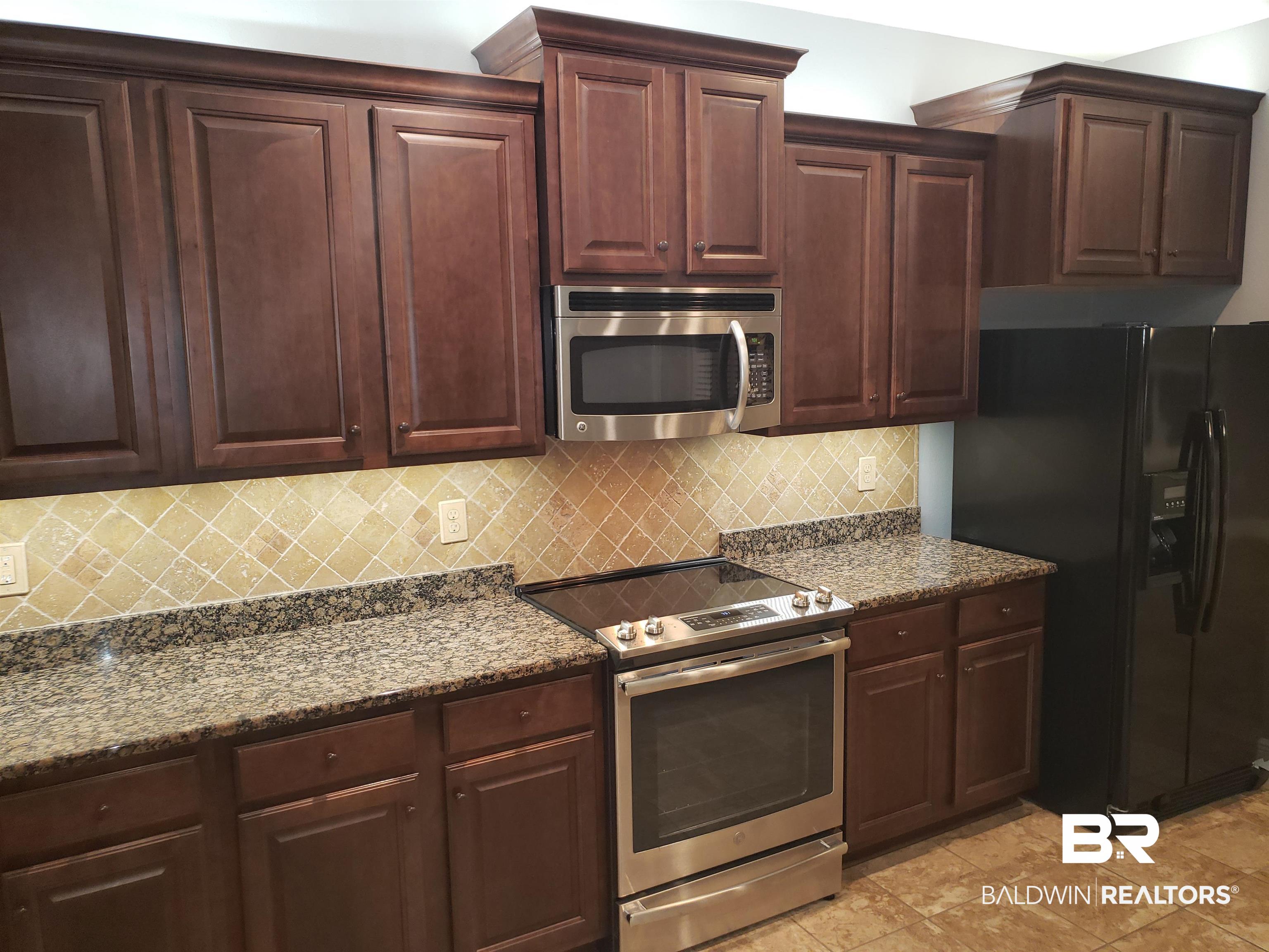 23373 Dundee Circle Foley, AL 36535 - Photo 8 of 34 Kitchen featuring stone countertops, tasteful backsplash, stainless steel appliances, and light tile patterned floors