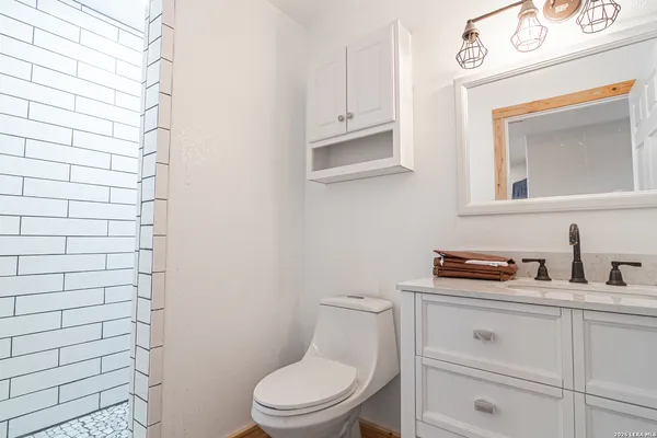 a bathroom with a toilet sink vanity and mirror