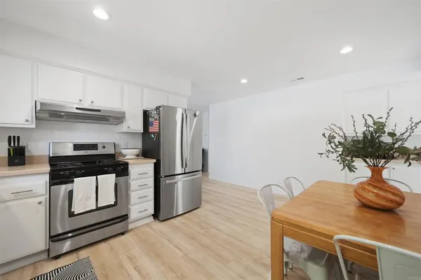 a kitchen with stainless steel appliances a sink a refrigerator a stove and white cabinets