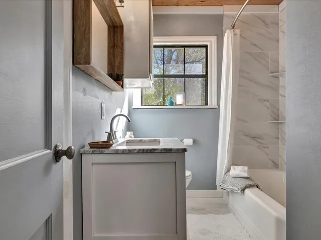 a bathroom with a granite countertop sink a toilet and shower