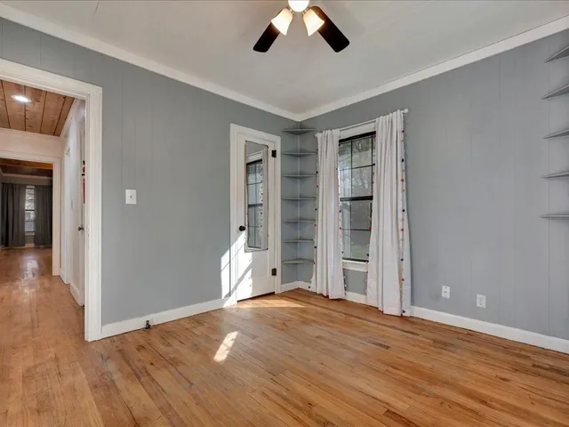 a view of an empty room with wooden floor and a window