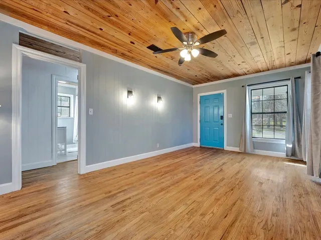 a view of an empty room with wooden floor and a window