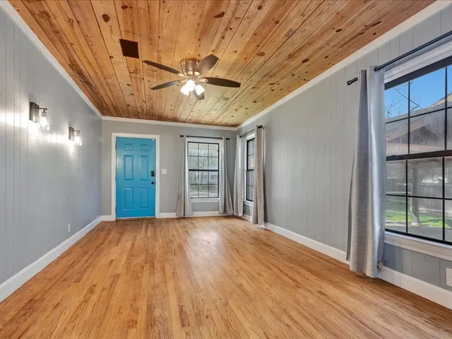 a view of empty room with wooden floor and fan