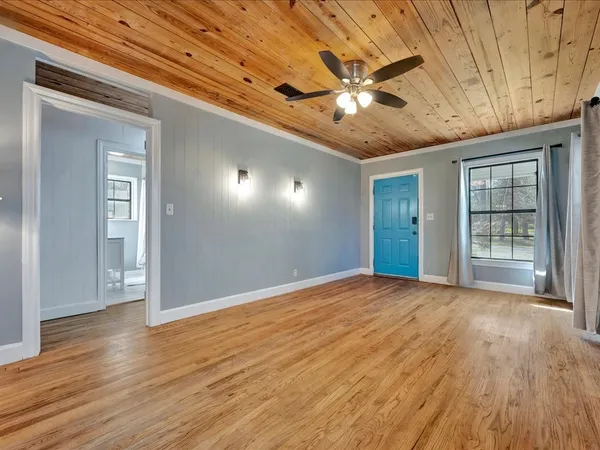 a view of an empty room with wooden floor and a window