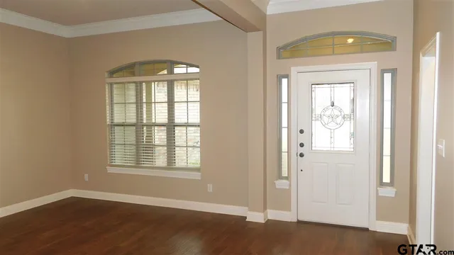 an empty room with wooden floor cabinet and windows