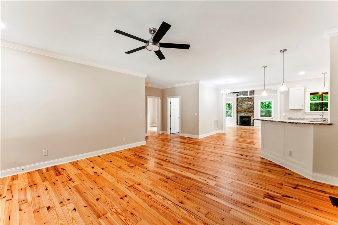 110 Gabriel Way Pickens, SC 29671 - Photo 5 of 48 Rich hardwood floors flow through this welcoming space, anchored by a sleek ceiling fan and stone fireplace.