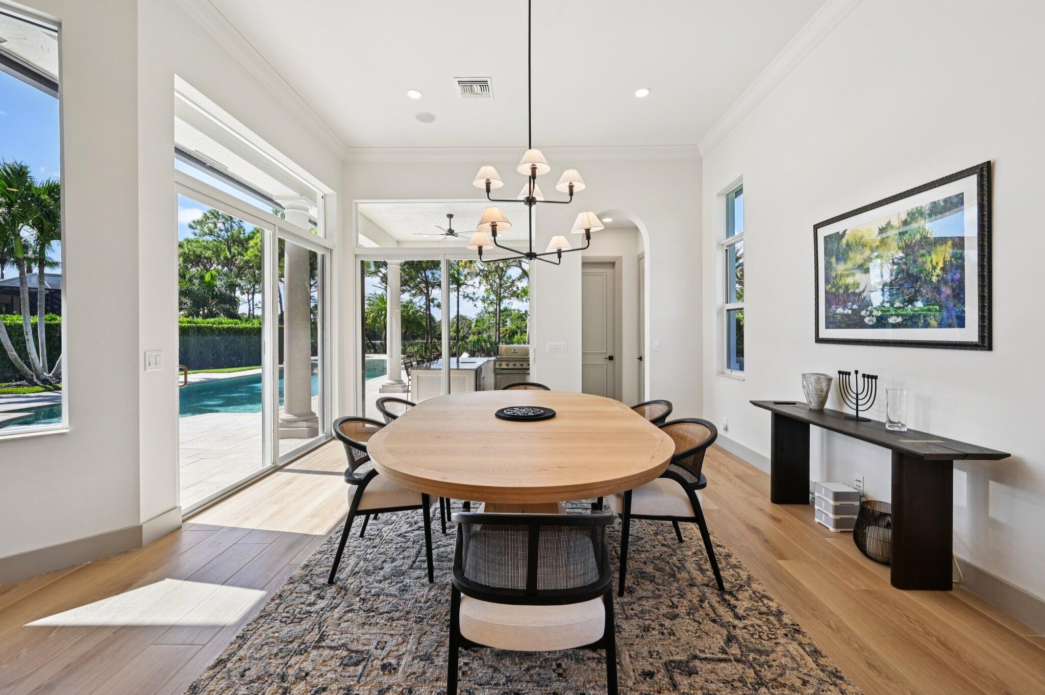 9936 Southeast Sandpine Lane Hobe Sound, FL 33455 - Photo 12 of 71 a dining room with wooden floor a chandelier a wooden table and chairs
