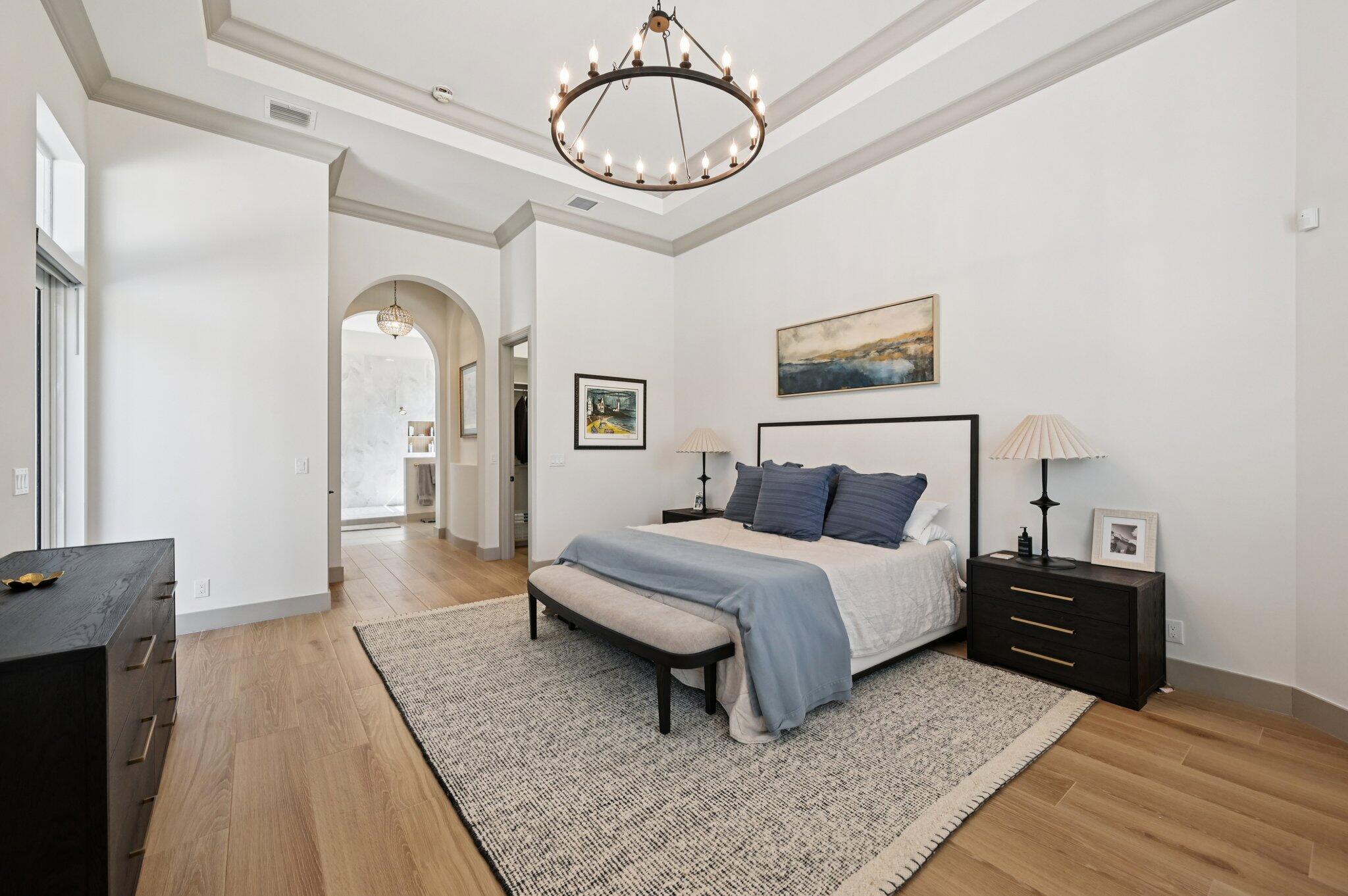 9936 Southeast Sandpine Lane Hobe Sound, FL 33455 - Photo 21 of 71 a spacious bedroom with a bed a mirror and lamp on desk