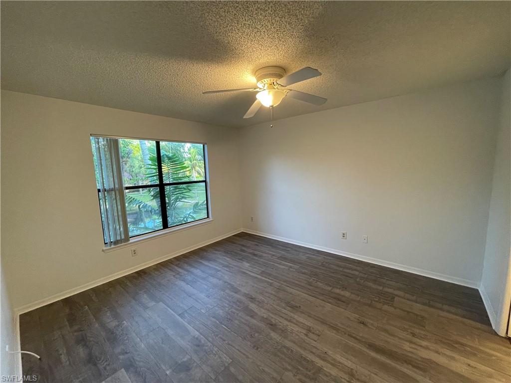 2142 Arbour Walk Circle, Unit 2624 Naples, FL 34109 - Photo 4 of 13 an empty room with wooden floor fan and windows