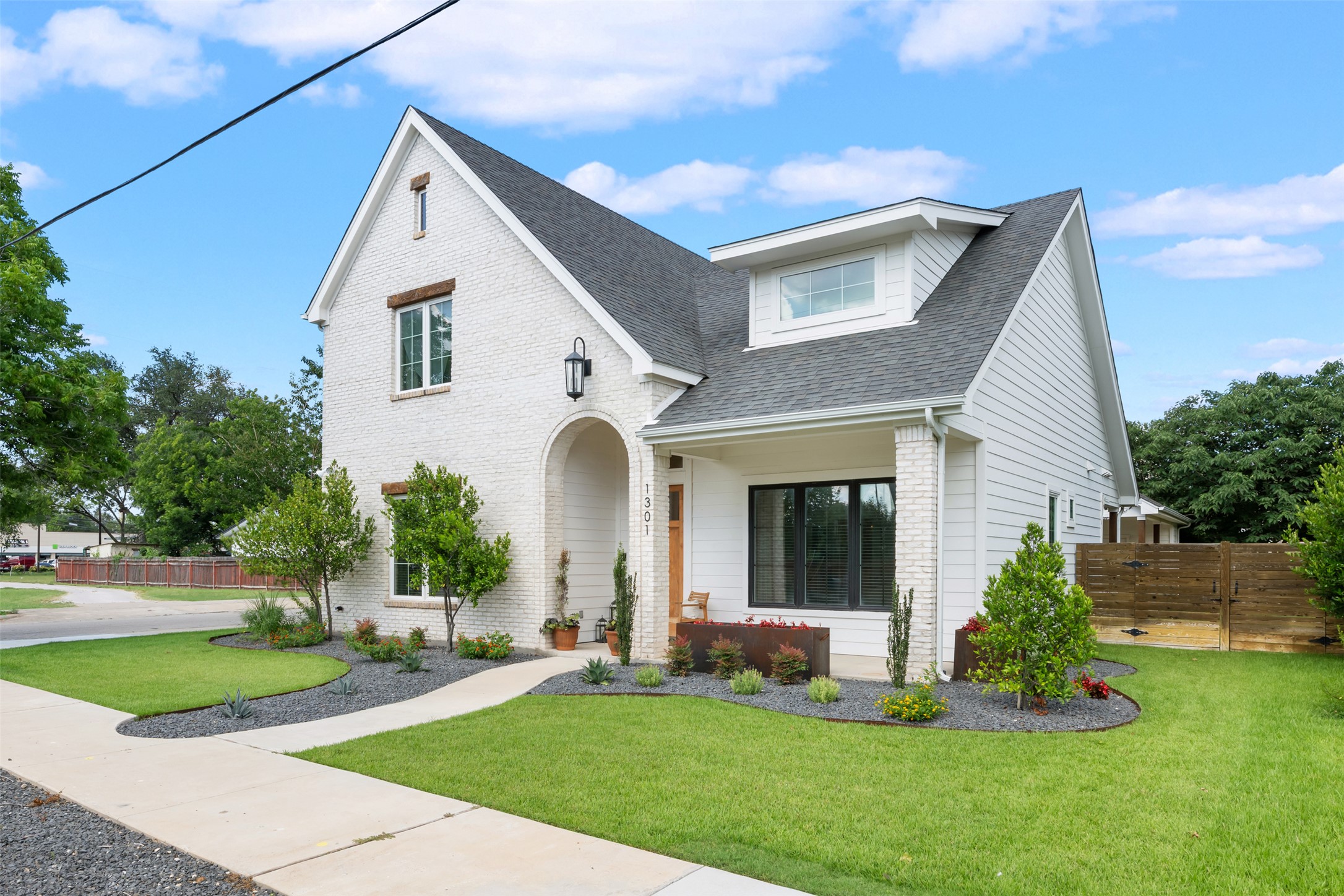 1301 West Street Georgetown, TX 78626 - Photo 3 of 40 A classic brick and siding residence boasts verdant landscaping and a welcoming arched entryway.