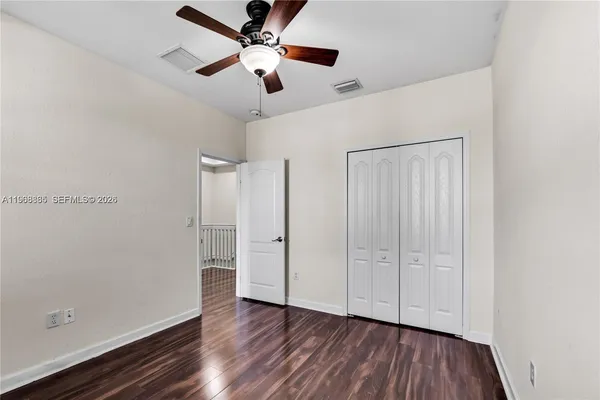 an empty room with wooden floor chandelier fan and closet area