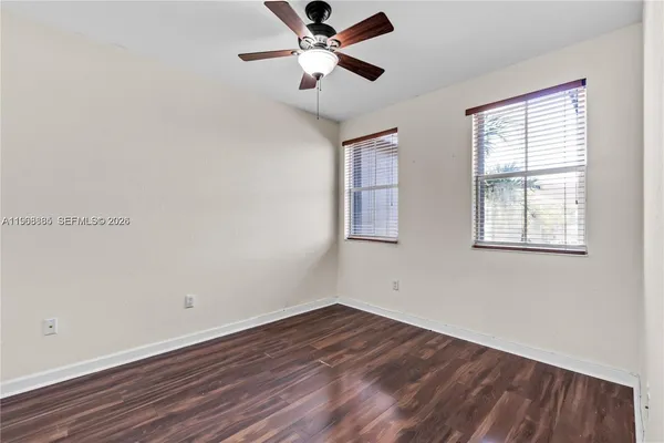 a view of empty room with wooden floor and fan