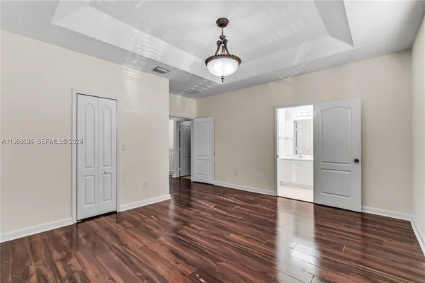 a view of an empty room with wooden floor and a ceiling fan