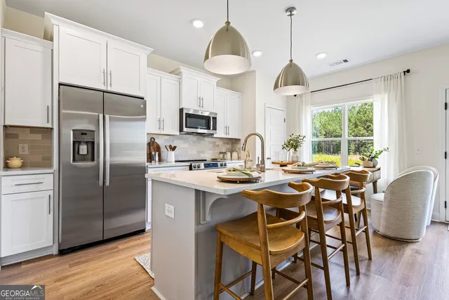 a kitchen with stainless steel appliances granite countertop a stove a refrigerator a oven a sink a island with a dining table and chairs