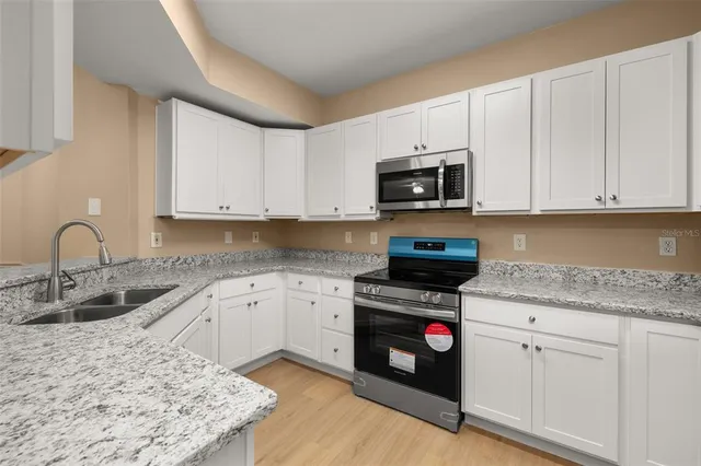 a kitchen with granite countertop a refrigerator stove and microwave