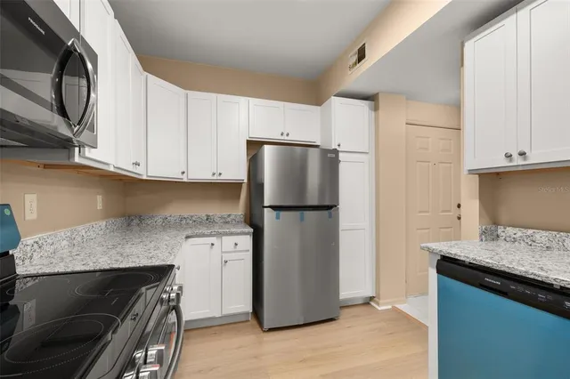 a view of an empty room with a window and a kitchen
