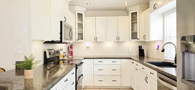 a kitchen with stainless steel appliances granite countertop a stove a sink and a white cabinets