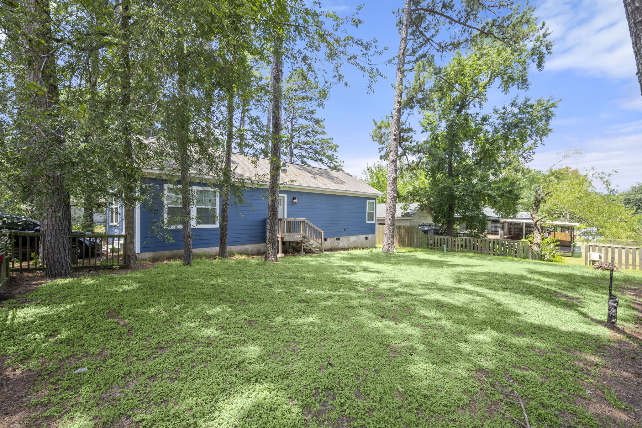 9649 Warm Spring Willis, TX 77318 - Photo 5 of 30 A spacious backyard awaits, offering a private outdoor retreat with a fenced perimeter and mature trees.