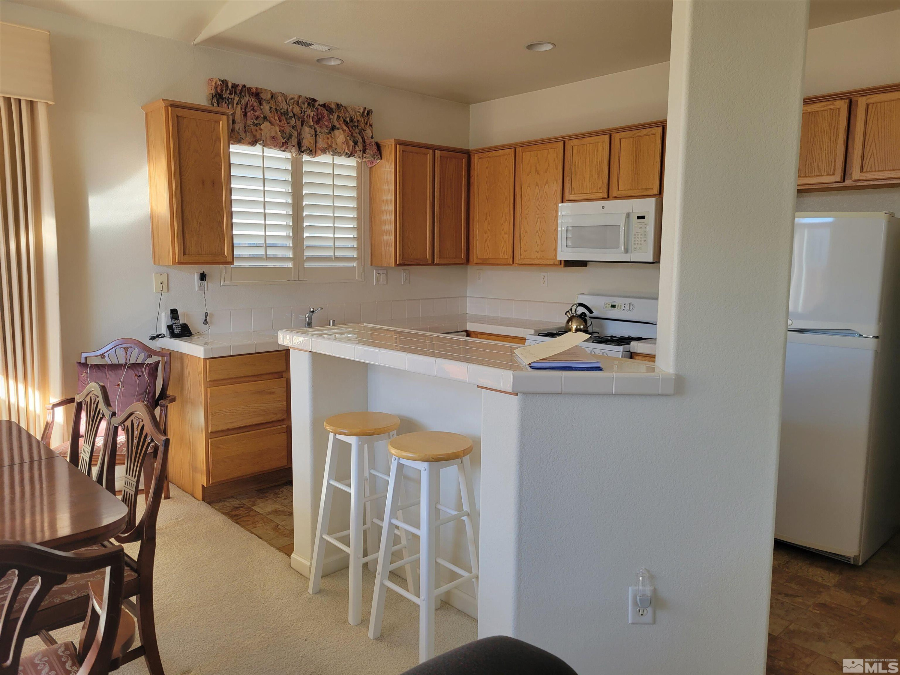 10415 Summershade Lane Reno, NV 89521 - Photo 7 of 15 a kitchen with stainless steel appliances a refrigerator a sink a stove a table and chairs