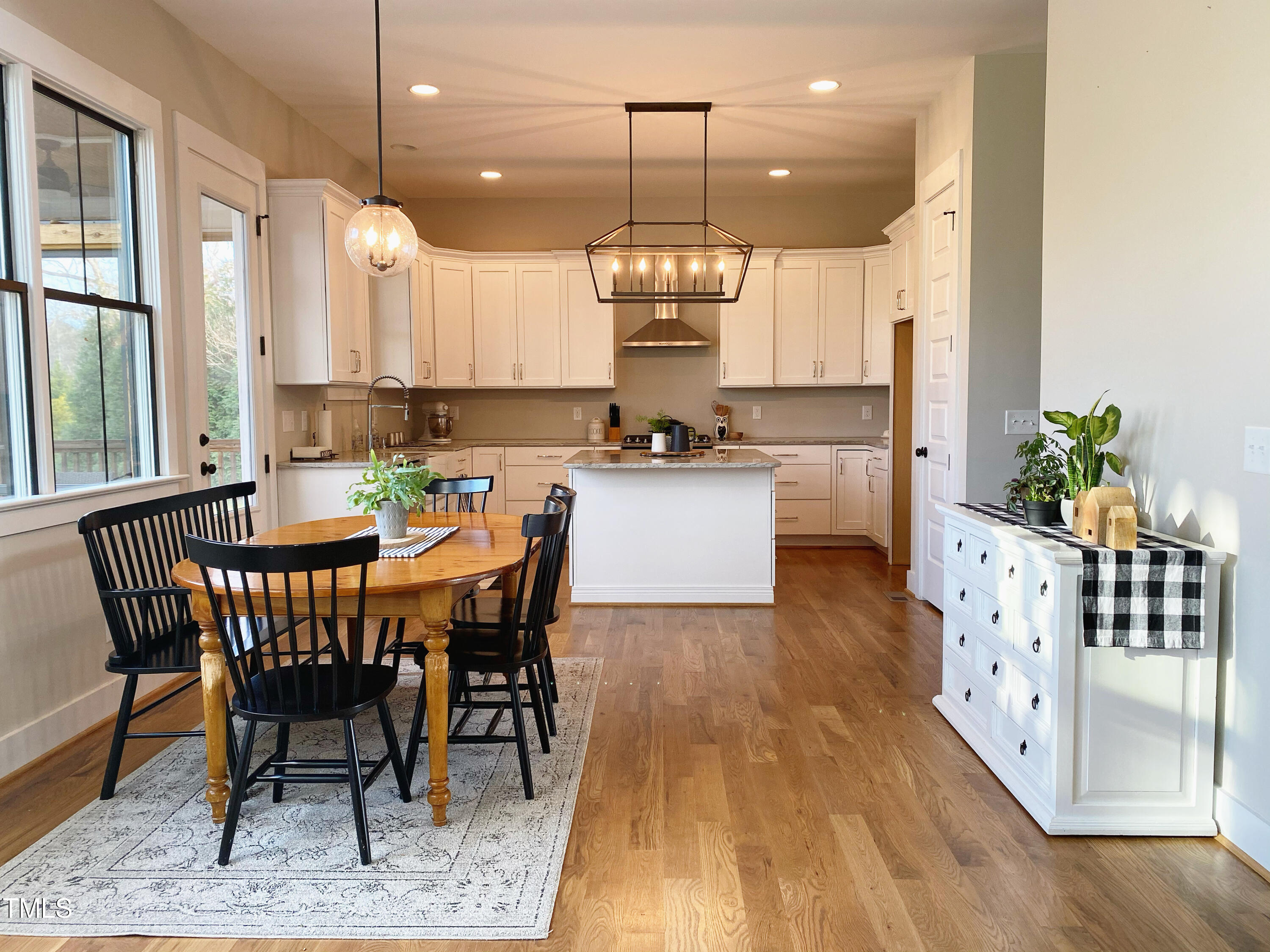 454 Waterville Street Raleigh, NC 27603 - Photo 6 of 25 a kitchen with stainless steel appliances kitchen island granite countertop a table chairs and a wooden floor