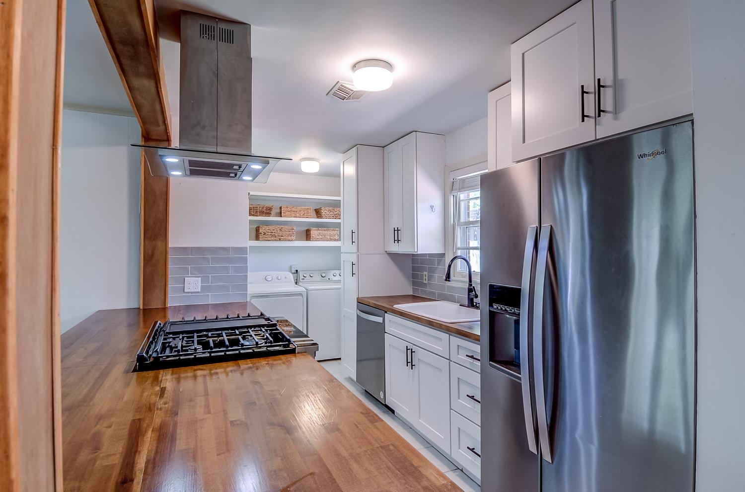 5056 Wingdale Road Memphis, TN 38117 - Photo 10 of 18 Kitchen with stainless steel appliances, wooden counters, island range hood, white cabinetry, and washing machine and dryer