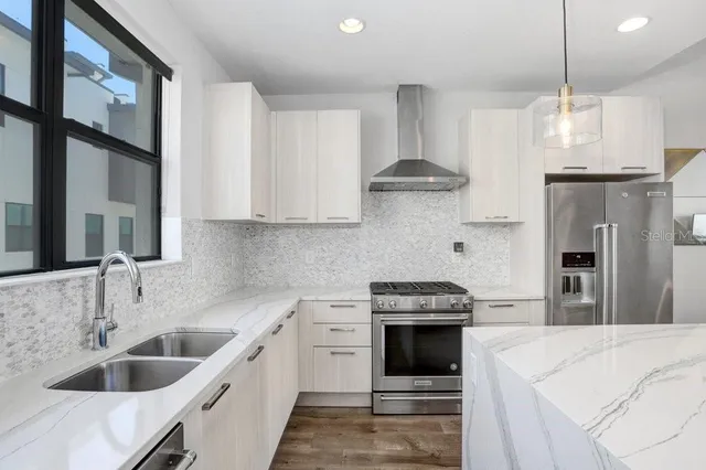 a kitchen with stainless steel appliances kitchen island a refrigerator sink and white cabinets