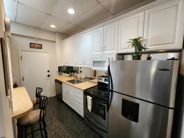 a kitchen with stainless steel appliances granite countertop a refrigerator a stove a sink dishwasher and white cabinets with wooden floor