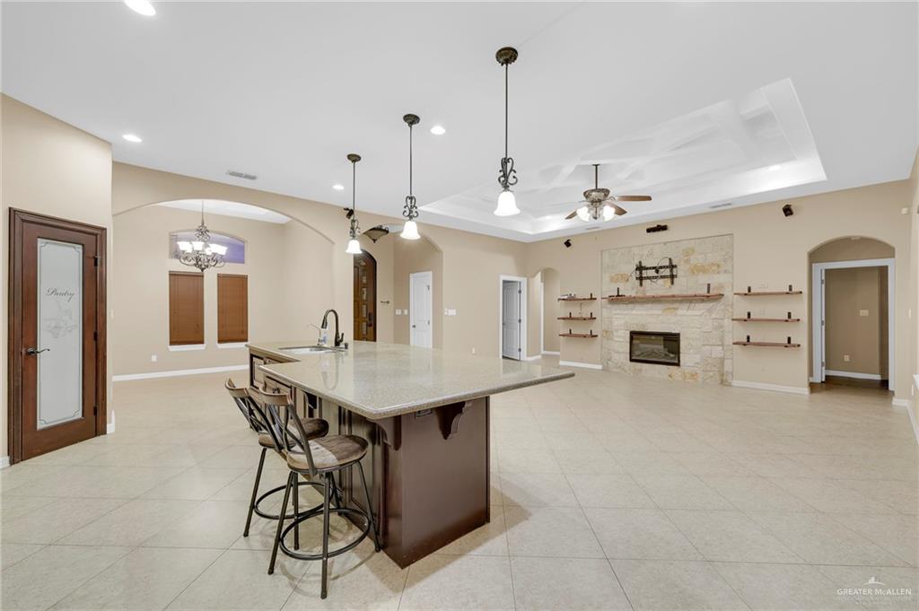1605 East 30th Street Mission, TX 78574 - Photo 3 of 16 Kitchen featuring arched walkways, decorative light fixtures, a kitchen bar, an island with sink, and light stone counters