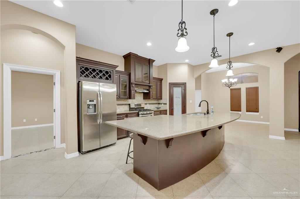 1605 East 30th Street Mission, TX 78574 - Photo 4 of 16 Kitchen with arched walkways, glass insert cabinets, tasteful backsplash, stainless steel appliances, and pendant lighting