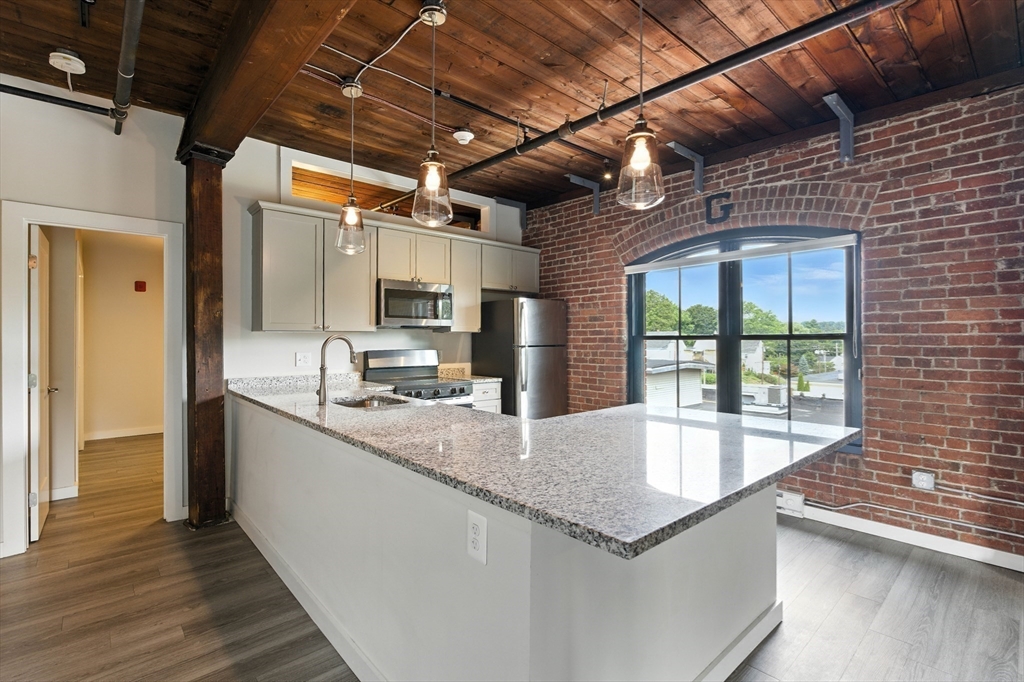 55 Sterling Street, Unit 306 Clinton, MA 01510 - Photo 4 of 32 a large kitchen with granite countertop a sink a counter space and stainless steel appliances