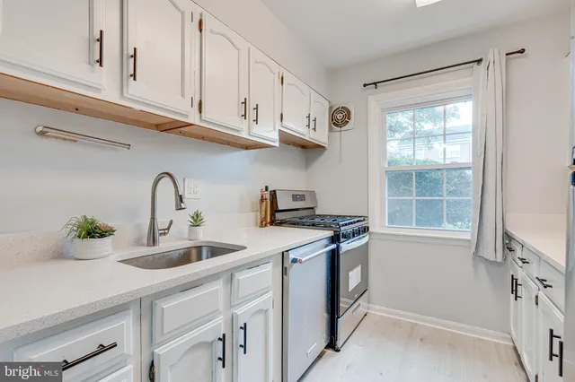 a kitchen with stainless steel appliances granite countertop a sink a stove and a window