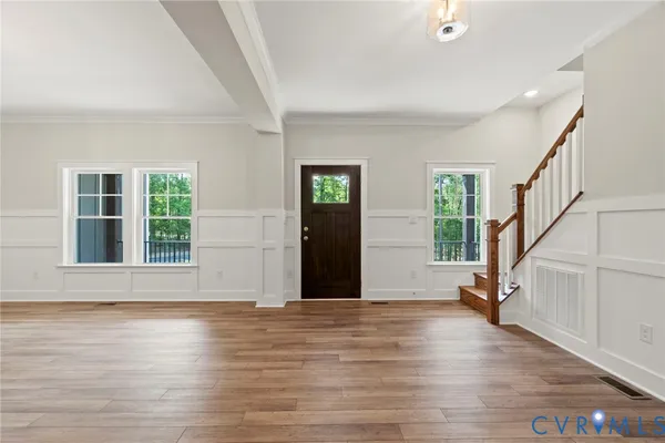 a view of an empty room with wooden floor fireplace and a window