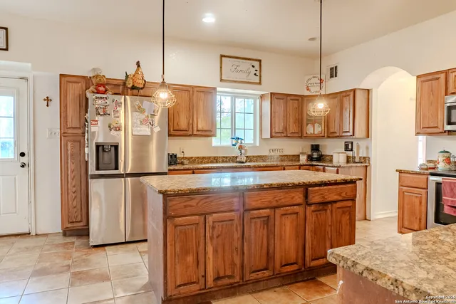 a kitchen with stainless steel appliances granite countertop a refrigerator a sink dishwasher a stove with white cabinets and countertops