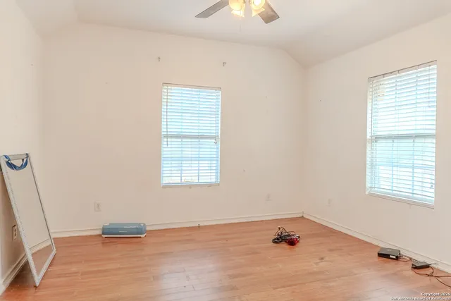 a view of empty room with wooden floor and fan