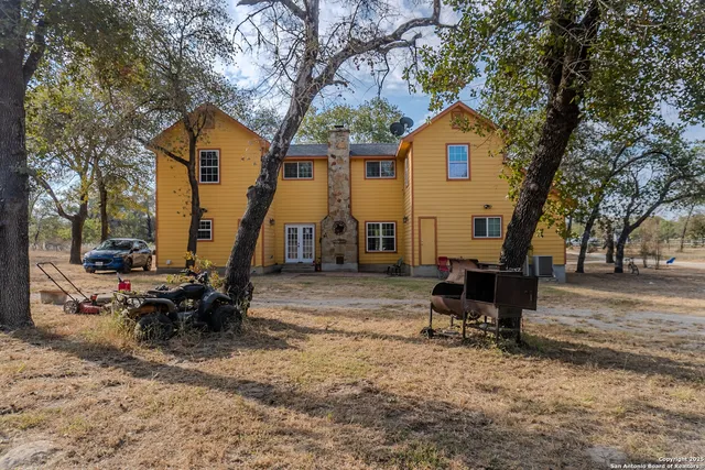 a view of a house with backyard and a tree